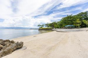 a sandy beach with trees and the water at Dominiks quite and Elegant Studio Ocean View Pool at Tambuli Resort High Floor in Maribago