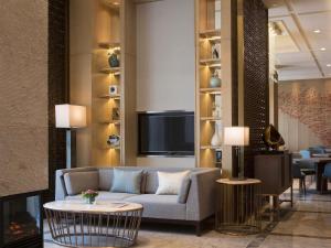 een woonkamer met een bank en een tv bij Pullman Taiyuan in Taiyuan