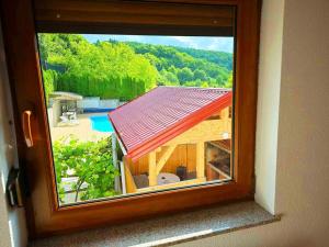 una finestra con vista su una casa e una piscina di Vikendica sa bazenom Cazin Pecigrad a Cazin