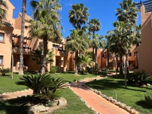 une cour d'un complexe hôtelier avec des palmiers dans l'établissement Casa Vera - apartment in Los Alcázares - Nueva Ribera Beach Club, à Los Alcázares