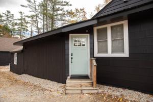 ein schwarzes Haus mit einer blauen Tür und einem Fenster in der Unterkunft Unwind at this Modern Bethel Village Escape in Bethel