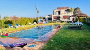 a swimming pool in a yard with people in it at Ferme royale Bensliman in Ben Slimane