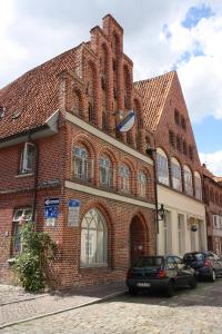 un grand bâtiment en briques avec une voiture garée devant. dans l'établissement Altstadt Gästehaus Drewes Wale, à Lunebourg