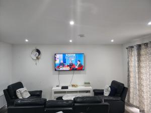 a living room with two black leather couches and a flat screen tv at Trinity Apartment in Highbridge