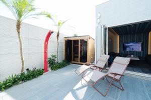 a pair of chairs on a patio with palm trees at リトルバーズホステル in Omihachiman