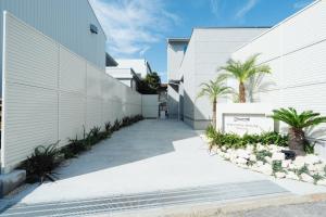 a white building with palm trees next to a sidewalk at リトルバーズホステル in Omihachiman
