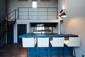 a kitchen with a blue island with white chairs at リトルバーズホステル in Omihachiman