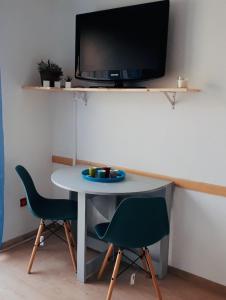 Una mesa con dos sillas y un televisor en una pared. en Le Balcon du Soleil studio climatisé Wifi coin nuit lit douillet proche cure et étang, en Balaruc-les-Bains