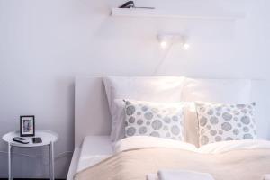 a bed with white sheets and pillows and a table at Extra Central NEW home with AC in Budapest