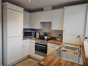 une cuisine avec des armoires blanches et un évier dans l'établissement Spacious 3-Storey Home from Home in Hetton le Hole, à Hetton le Hole