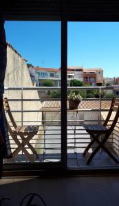 Una vista de un balcón con dos sillas y una mesa. en Le Balcon du Soleil studio climatisé Wifi coin nuit lit douillet proche cure et étang, en Balaruc-les-Bains