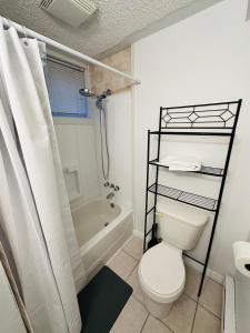 a white bathroom with a toilet and a shower at Oscar's Retreat - 1Bedroom Apart in Moncton
