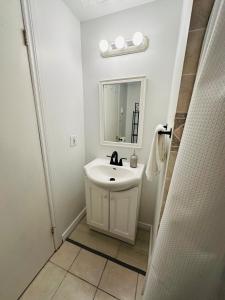 a white bathroom with a sink and a mirror at Oscar's Retreat - 1Bedroom Apart in Moncton +9 photos