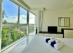 a bedroom with a large white bed with a large window at Sunset Plaza by RESAVA in Karon Beach
