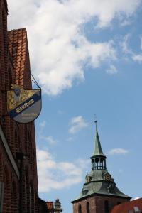 un panneau sur le côté d'un bâtiment avec une tour dans l'établissement Altstadt Gästehaus Drewes Wale, à Lunebourg