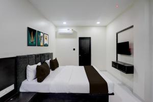 1 dormitorio con 1 cama blanca grande con almohadas negras en Hotel O Laxmi Lodging, en Aurangabad