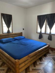 a bedroom with a bed with blue sheets and two windows at GELATHAÏ Home in Ko Phayam