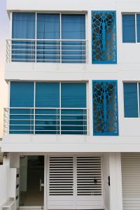 a white building with blue windows and a balcony at Apartamento 301 - Edificio Salomon Diaz in Santa Marta