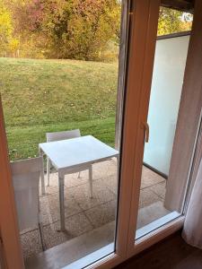 une table blanche et une chaise devant une porte dans l'établissement L,orchidée, à Équemauville