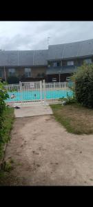 einem Pool mit einem weißen Zaun vor einem Gebäude in der Unterkunft L,orchidée in Équemauville + 2 Fotos
