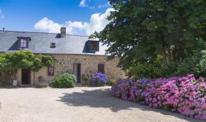 une maison en pierre avec des fleurs violettes devant elle dans l'établissement La Ferme de Kerraoul, à Combrit