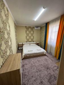 a bedroom with a bed and a table in it at Гостевой дом Энесай in Bishkek