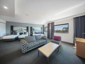 ニューカッスルにあるMercure Newcastle Airportのベッドとリビングルームがあるホテルの部屋