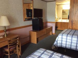 a hotel room with a bed and a desk with a television at The Royal Inn in Ridgway