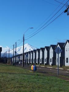 a row of houses on a street with a snow covered mountain at Cabaña Villarrica Los Carpinteros in Villarrica
