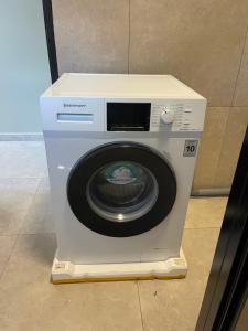 een witte wasmachine op de vloer bij Majestic Apartment 1 Tout lui Faut in Flora