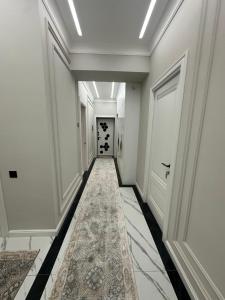 een hal met witte muren en een tapijt op de vloer bij Prime House Samarkand 2 in Samarkand