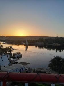 ein Sonnenuntergang über einem Yachthafen mit einem Segelboot im Wasser in der Unterkunft El Prince Guesthouse in Assuan