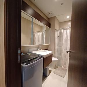 a bathroom with a sink and a toilet and a mirror at Tambuli Seaside Living Tower F, Unit J Level 15 in Maribago