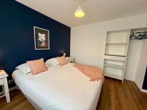 a bedroom with a large bed with a blue wall at L'Abalone 3 Étoiles in Aizenay