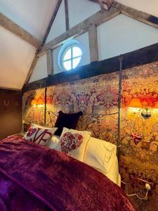 ein Schlafzimmer mit einem Bett und einer Wand mit einem Fenster in der Unterkunft Country Cottage and Converted Barn Suite in Cholderton + 19 Fotos