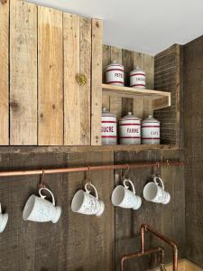 eine Reihe weißer Tassen, die an einer Wand hängen in der Unterkunft Country Cottage and Converted Barn Suite in Cholderton