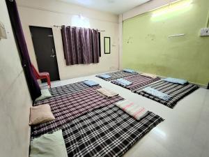 two beds in a room with blankets on the floor at Durga Bhakt Niwas in Tuljapur +4 photos
