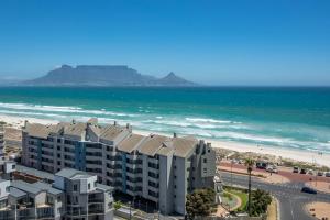 Blick auf einen Strand mit einem Gebäude und dem Meer in der Unterkunft Luxurious 3-bedroom Bloubergstrand Cape Town beachfront apartment with stunning sea and beach view in Cape Town