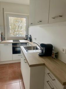 a white kitchen with a sink and a window at Your home away from home in Osnabrück
