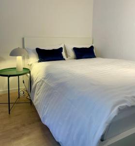 a large white bed with blue pillows next to a table at Your home away from home in Osnabrück