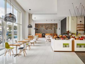 un restaurant avec des tables et des chaises et une cuisine dans l'établissement Mercure Sohar, à Sohar