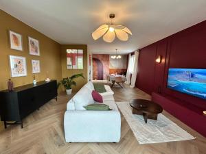 a living room with a white couch and a tv at Maison B - Mont Saint Michel in Marcey-les-Grèves