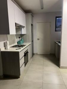 Una cocina con gabinetes blancos y un horno de estufa. en Modern Apartment in Centurion, en Centurion 14 fotos más