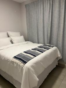 Una cama blanca con una manta blanca y negra encima. en Modern Apartment in Centurion, en Centurion