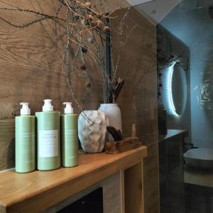 een plank met drie groene shampooflessen en een vaas bij Aftăr Hills in Poiana Mărului