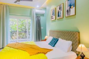 a bedroom with a bed with a yellow blanket and a window at Zephyr Luxury 2BHK With Private Jacuzzi Nr Anjuna in Siolim