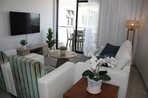 ein Wohnzimmer mit einer weißen Couch und einem Tisch in der Unterkunft Luxurious 3-bedroom Bloubergstrand Cape Town beachfront apartment with stunning sea and beach view in Cape Town