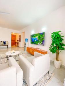 ein Wohnzimmer mit weißen Möbeln und einem Flachbild-TV in der Unterkunft Majestic Apex Residence in Bamburi
