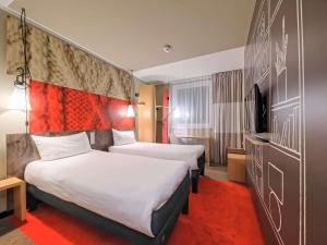 a hotel room with two beds and a tv at Ibis Gdansk Stare Miasto in Gdańsk