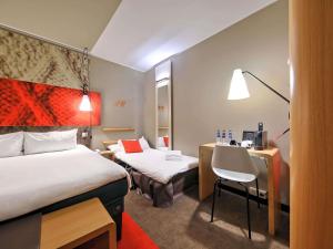 a hotel room with two beds and a desk at Ibis Gdansk Stare Miasto in Gdańsk +82 photos
